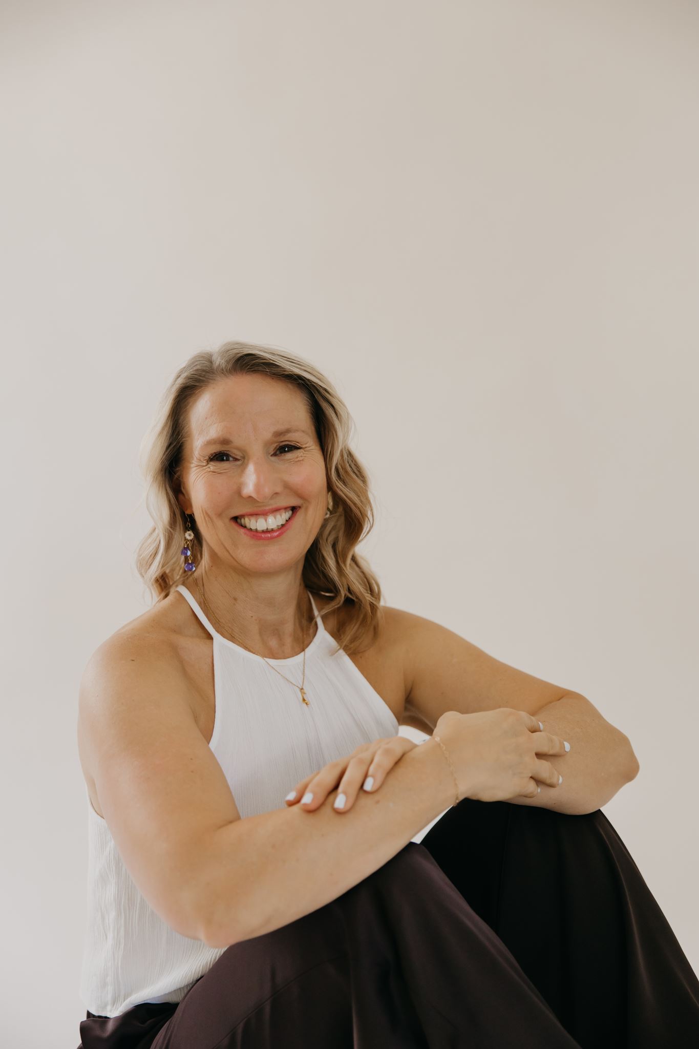 Kristen smiling, seated against a warm neutral background
